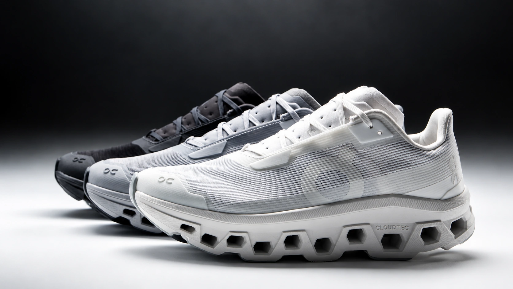 Trois sneakers On Cloud noire, grise et blanche, avec la blanche au premier plan